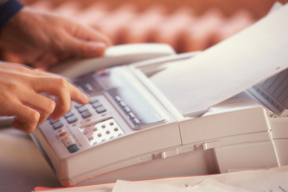 File photo of a person using a fax machine. / Credit: iStock/Getty