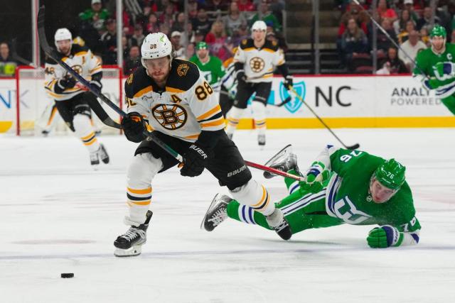Boston Bruins right wing David Pastrnak (88) and Carolina Hurricanes defenseman Brady Skjei (76) chase after the loose puck during the second period at PNC Arena.