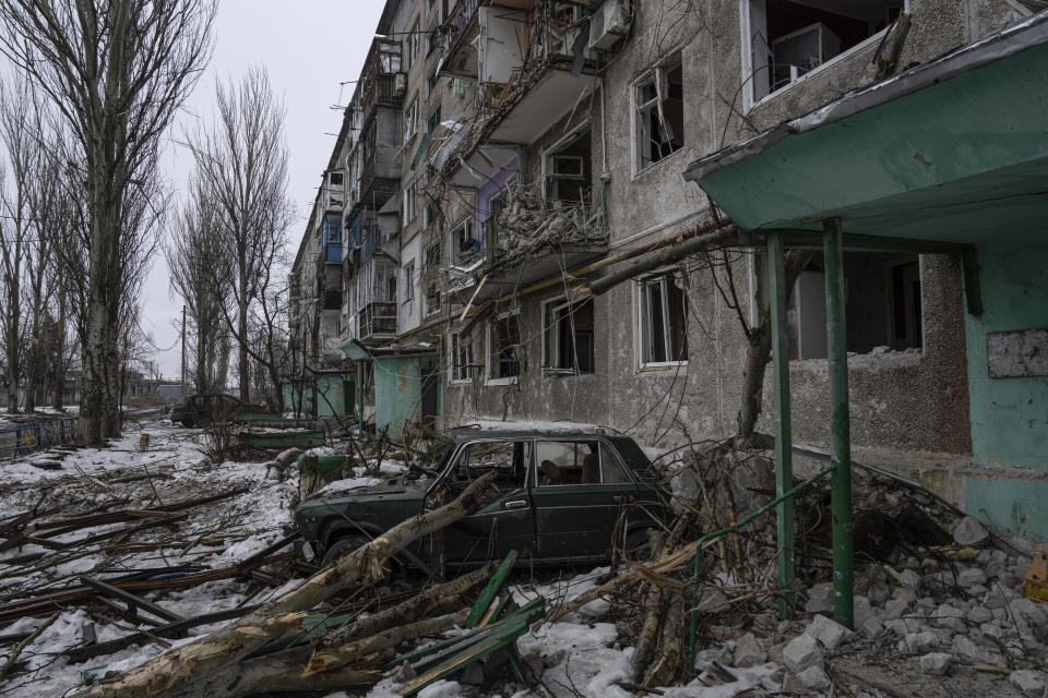 A destroyed car is seen in front of a residential building which was heavily bombed by Russian forces, in the frontline city of Vuhledar, Ukraine, Saturday, Feb. 25, 2023. (AP Photo/Evgeniy Maloletka)