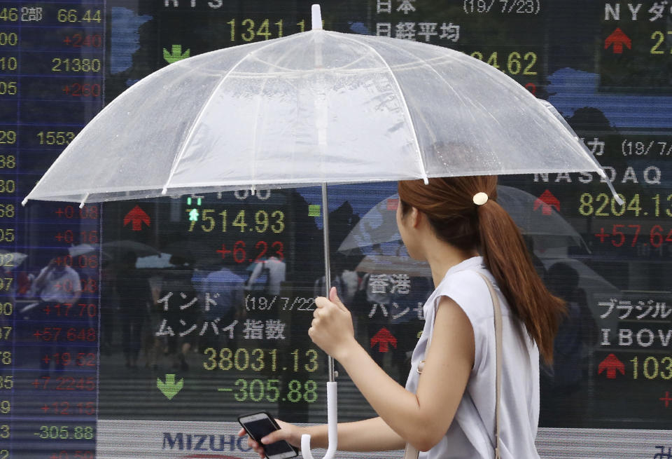 A woman walks by an electronic stock board of a securities firm in Tokyo, Tuesday, July 23, 2019. Asian stock markets rose on Tuesday on optimism over possible new U.S.-China talks despite rising Middle East tensions. (AP Photo/Koji Sasahara)