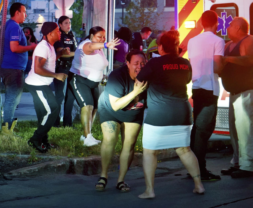 A woman reacts as emergency response crews move wounded people to ambulances after multiple people were shot at a party Saturday, June 20, 2020, in Syracuse, N.Y. Nine people were shot and one victim, a 17-year-old boy, was in critical condition Sunday. (Ellen M. Blalock/Syracuse Post-Standard via AP)