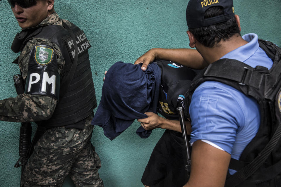 <p>During a military police operation in Hato de Enmedio neighborhood in the capital Tegucigalpa, a young men allegedly belonging to the 18th street criminal gang, or Mara-18, is escorted away. (Photo: Francesca Volpi) </p>