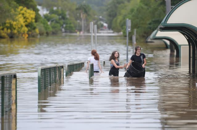 Girls walk through floodwaters as they recede in Lismore. Source: AAP