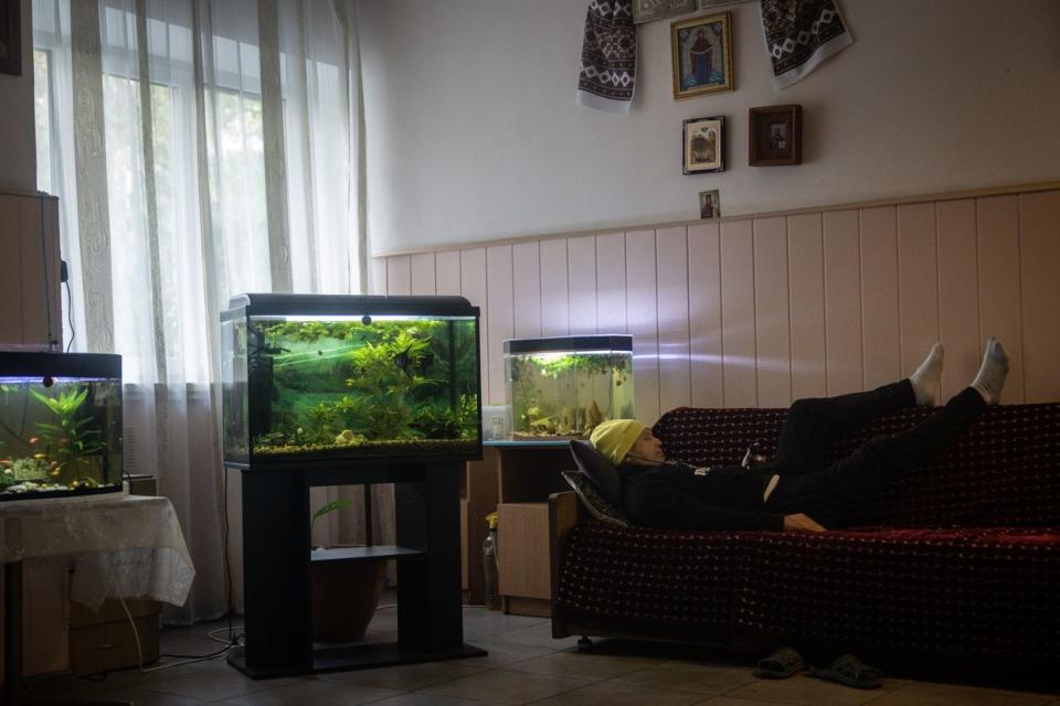 A Ukrainian soldier suffering from trauma watches a movie on his phone next to fish tanks at a psychiatric hospital in Kyiv, Ukraine, on Oct. 5, 2023. (PhotChris McGrath/Getty Images)