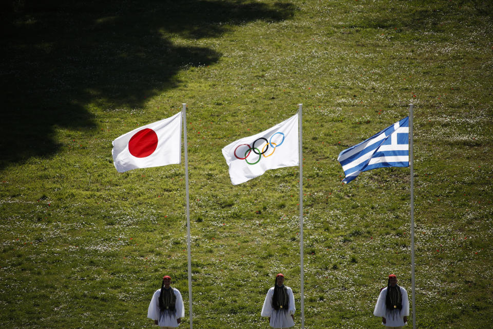 Greek Evzones guards stand next to Japan, Olympic and Greece flags, from left, during the flame lighting ceremony at the closed Ancient Olympia site, birthplace of the ancient Olympics in southern Greece, Thursday, March 12, 2020, 2020. Greek Olympic officials are holding a pared-down flame-lighting ceremony for the Tokyo Games due to concerns over the spread of the coronavirus. Both Wednesday's dress rehearsal and Thursday's lighting ceremony are closed to the public, while organizers have slashed the number of officials from the International Olympic Committee and the Tokyo Organizing Committee, as well as journalists at the flame-lighting. (AP Photo/Yorgos Karahalis)