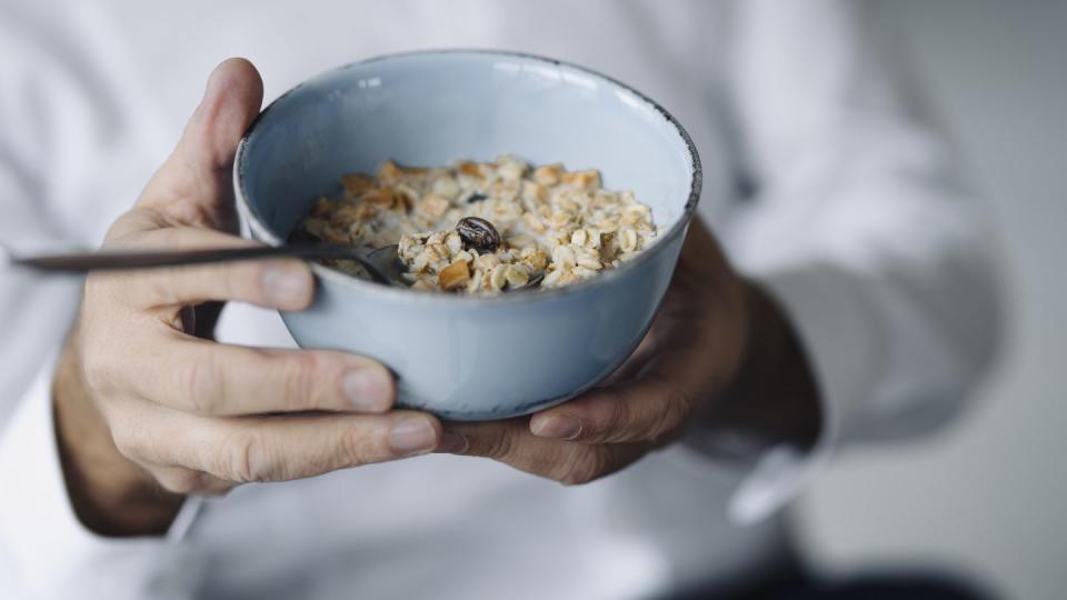 man's hands holding cereal bowl, close up