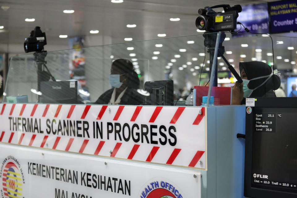 A Malaysian health quarantine officer waits for passengers at a thermal screening point at the international arrival terminal of Kuala Lumpur International Airport in Sepang. WHO has advised the Malaysian government to prepare itself for the possibility of a wider transmission of Covid-19. — Reuters pic