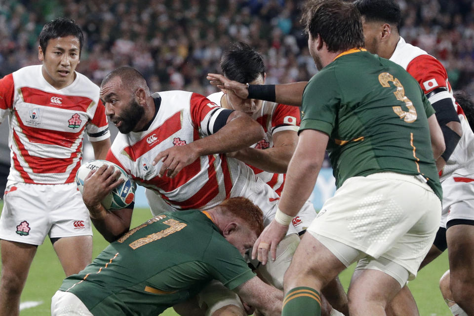 FILE - Japan's Michael Leitch is tackled by South Africa's Steven Kitshoff during the Rugby World Cup quarterfinal match at Tokyo Stadium between Japan and South Africa in Tokyo, Japan, on Oct. 20, 2019. Japan has been a fan favorite at the last two Rugby World Cups for its underdog victories over top-tier teams. (AP Photo/Mark Baker, File)