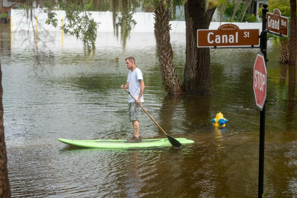 Chris Bodue paddles Wednesday through his neighborhood in Tarpon Springs that had been flooded by Hurricane Idalia.