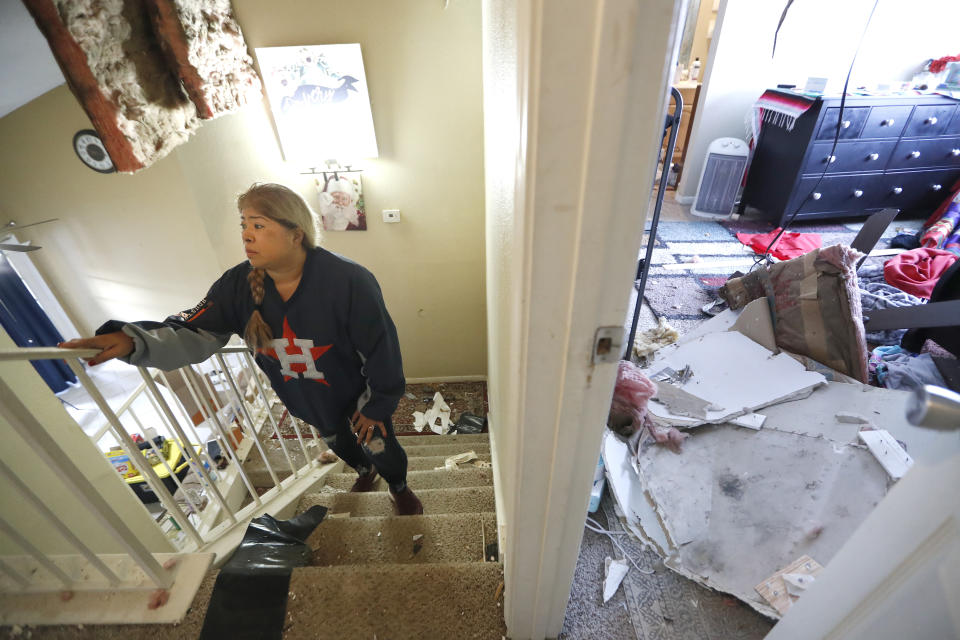 Maria Hernandez climbs her stairwell as she and her family worked to move their belongings out as they sifted through their damaged home in the Bridgeland Lane area of Houston, Sunday, Jan. 26, 2020, after the Watson Grinding Manufacturing explosion early Friday morning. Her ceiling, right, collapsed even further after overnight rains. (Karen Warren/Houston Chronicle via AP)