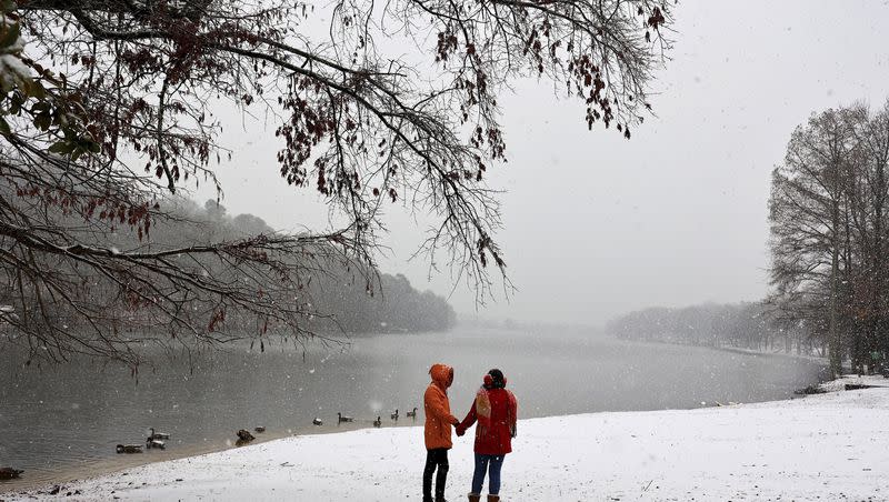 Taylor Cannon, left, and Darby Tanner visit Lake No. 1 as snow falls Friday morning, Jan 5, 2024, in the Lakewood area of North Little Rock, Ark. 