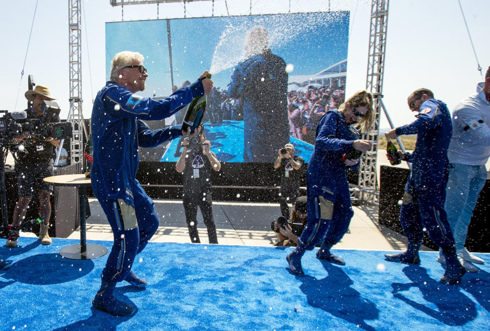 Virgin Galactic founder Richard Branson, left, sprays champagne to his crew members while celebrating their flight to space from Spaceport America near Truth or Consequences, N.M., Sunday, July 11, 2021. (AP Photo/Andres Leighton)
