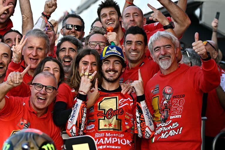 Pecco Bagnaia celebra junto al equipo Ducati y a su novia Domizia el título; el italiano enseña los tres anillos mundiales, uno en Moto2, en 2018