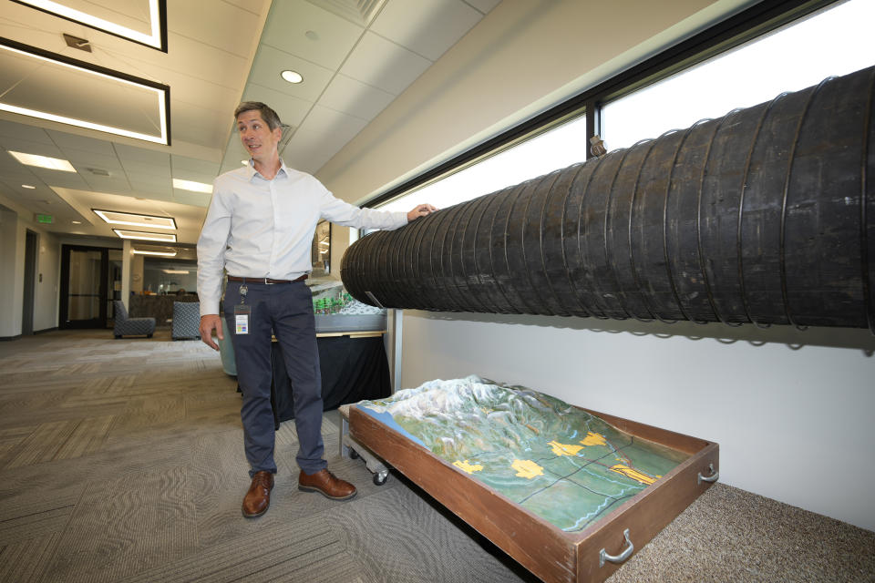 In this Monday, July 26, 2021, photograph, Adam Jokerst, deputy director of water resources for the City of Greeley, Colo., Water Department, explains what type of pipe was once used to carry water to the community but now makes up a display in the water department in Greeley, Colo. Figures released this month show that population growth continues unabated in the South and West, even as temperatures rise and droughts become more common. That in turn has set off a scramble of growing intensity in places like Greeley to find water for the current population, let alone those expected to arrive in coming years. (AP Photo/David Zalubowski)