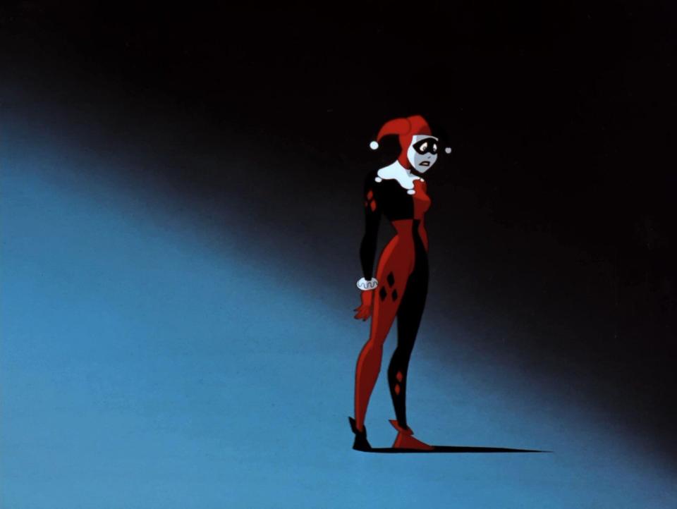 harley quinn in her jester outfit in batman the animated series, looking sad against a shadowy blue background