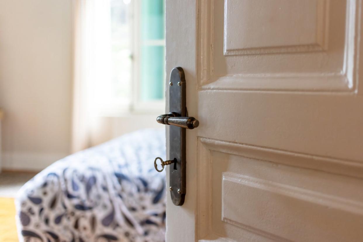 Door open, blur elegant hotel room, bedroom interior. Retro door knob on white door, close up