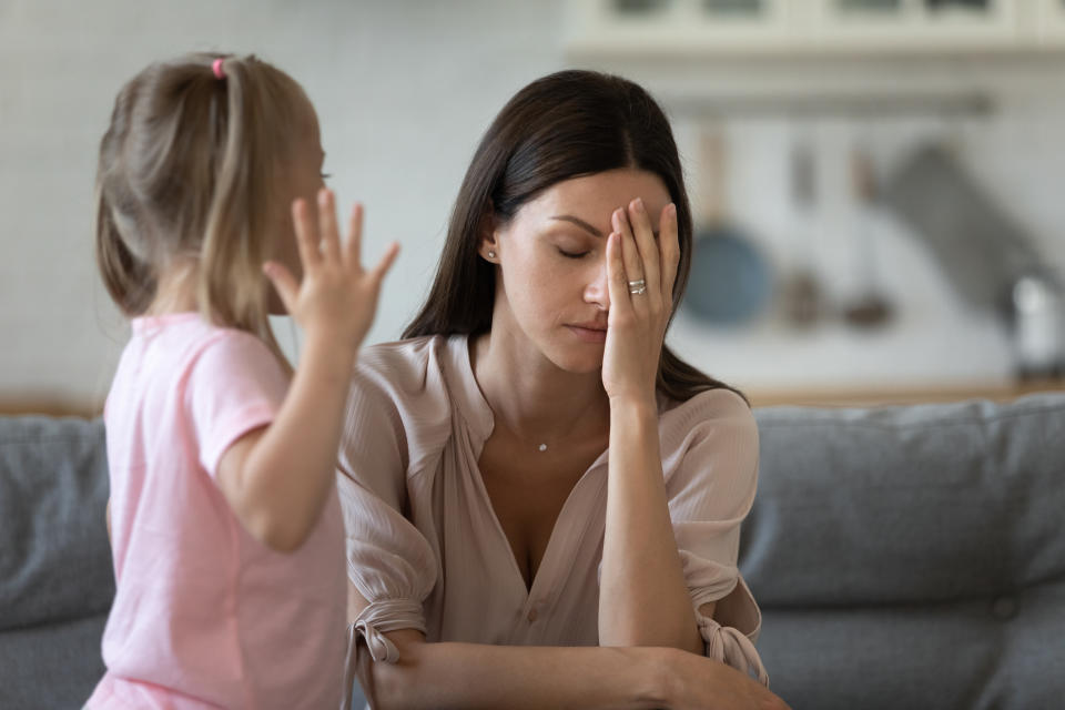 a mother looking tired as her kid stands in front of her