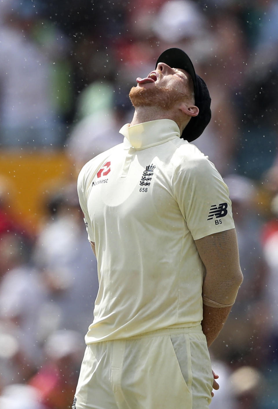 England's Ben Stokes tries to catch a few drops of rain during a drizzle on day three of the first cricket Test match against West Indies at the Kensington Oval in Bridgetown, Barbados, Friday, Jan. 25, 2019. (AP Photo/Ricardo Mazalan)