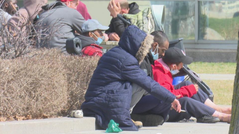 People experiencing homelessness sit outside of a temporary shelter in downtown Windsor, Ont.