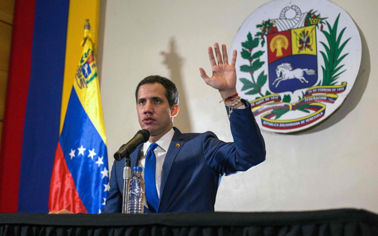 Juan Guaido raises his hand during a National Assembly session in November - CRISTIAN HERNANDEZ/AFP