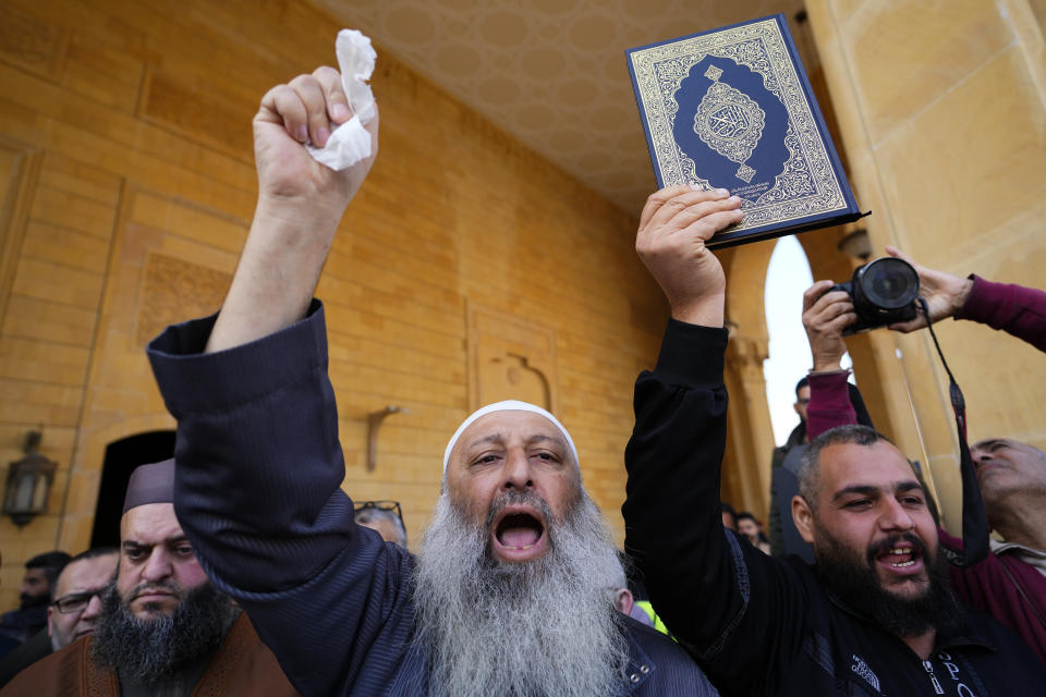 Protesters shout slogans and raise the Quran, the Muslim holy book, before burning the Swedish and Netherlands flags after Friday prayers outside Mohammad al-Amin Mosque to denounce the recent desecration of Islam's holy book by a far-right activists in the European countries in downtown Beirut, Lebanon, Friday, Jan. 27, 2023. Earlier this month, a far-right activist from Denmark received permission from police to stage a protest outside the Turkish Embassy in Stockholm where he burned the Quran, Islam's holy book. Days later, Edwin Wagensveld, Dutch leader of the far-right Pegida movement in the Netherlands tore pages out of a copy of the Quran near the Dutch parliament and stomped on the pages. (AP Photo/Hassan Ammar)