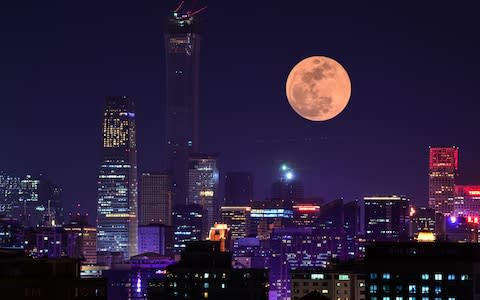 A super blood moon rises over buildings on January 31, 2018 in Beijing, China - Credit: VCG