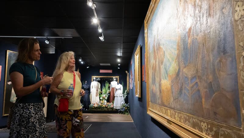 Anne Penrod, left, and Anne Albaugh, right, both painters from Salt Lake City, admire Minerva Teichert’s painting “The Women of Utah Save the Day” during an exhibit at  Anthony's Fine Art & Antiques in Salt Lake City on Wednesday, July 3, 2024. Both Penrod and Albaugh said they admire Teichert’s work because it was rare for a woman to be an artist in her era.