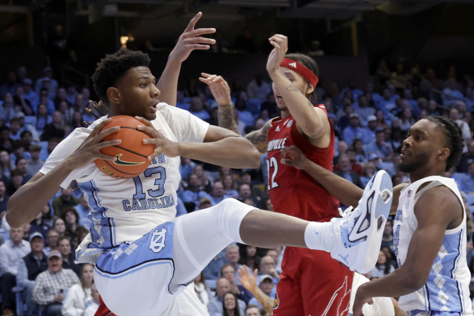 North Carolina forward Jalen Washington (13) grabs a rebound as teammate Jae'Lyn Withers, right, and Louisville guard Tre White, center, watch during the second half of an NCAA college basketball game Wednesday, Jan. 17, 2024, in Chapel Hill, N.C. (AP Photo/Chris Seward)