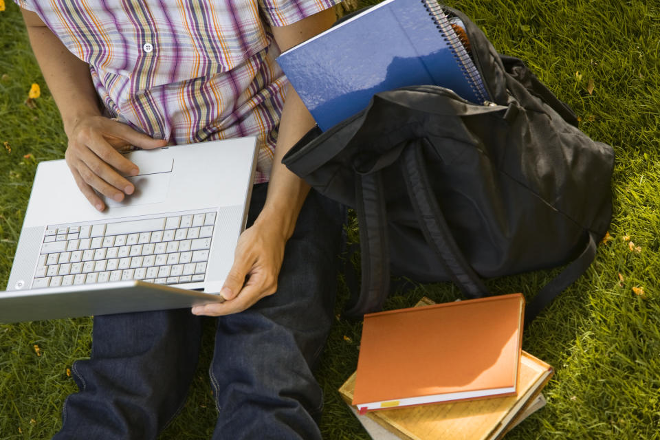 Student on campus studying with their Chromebook laptop and books.