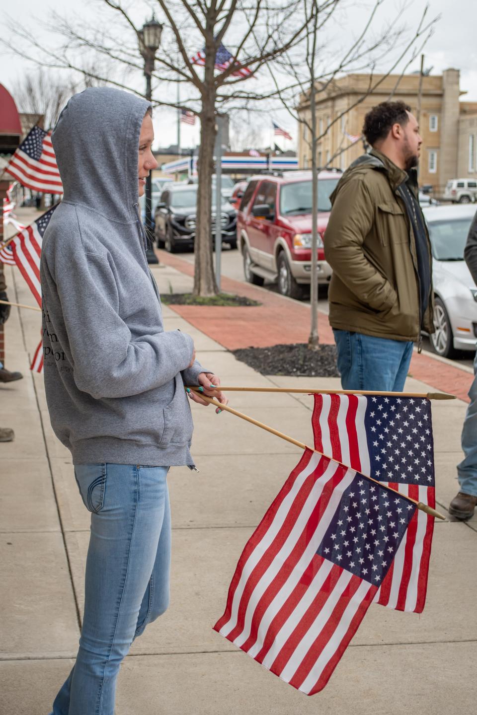 Melissa West waits for the procession for Sgt. Speedy to make its way to the Thorn-Black Funeral Home. Crowds lined Wheeling Avenue, waving flags and showing their respect for the fallen soldier.