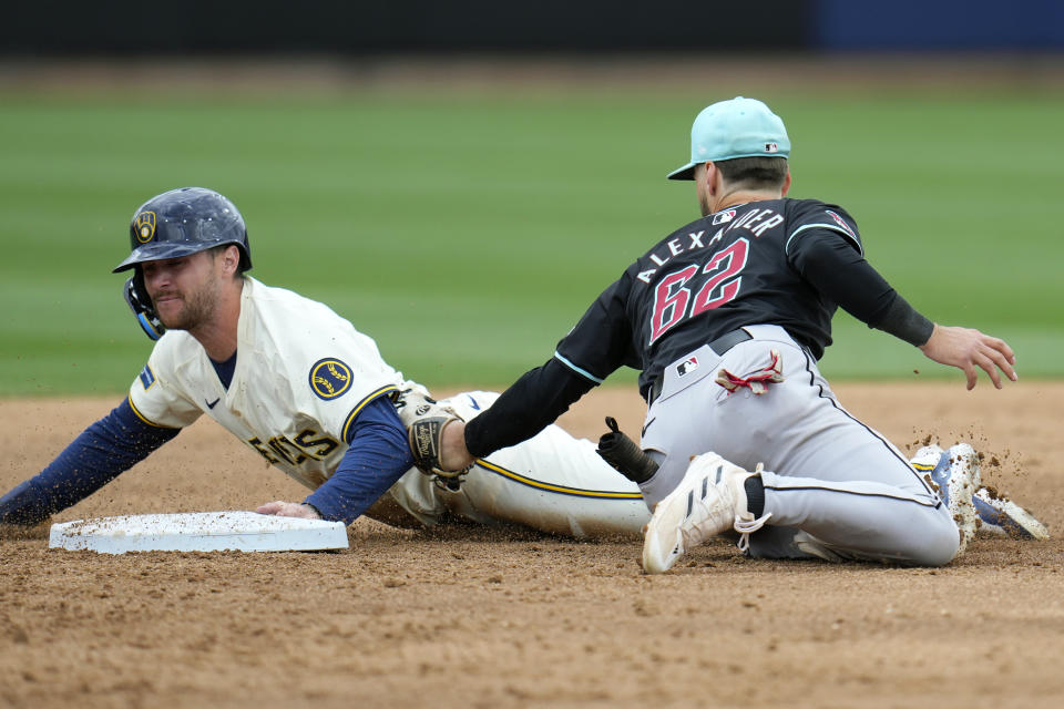 Milwaukee Brewers' Brice Turang, left, steals second base as Arizona Diamondbacks second baseman Blaze Alexander (62) applies a late tag during the second inning of a spring training baseball game Sunday, March 24, 2024, in Phoenix. (AP Photo/Ross D. Franklin)