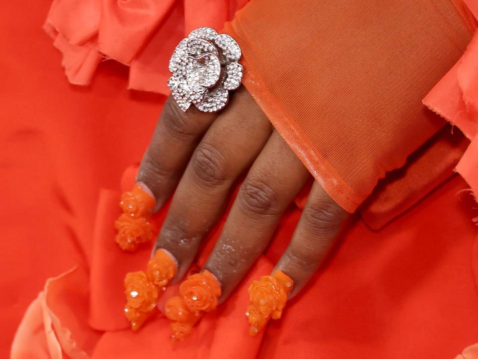 A close-up photo of Lizzo's nails featuring 3D floral appliqués at the 2023 Grammys.