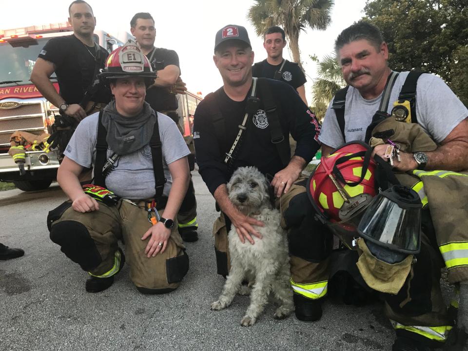 Indian River County Fire Rescue firefighters pose with "Lucky" who they saved from burning home in the 500 block of Caribbean Circle off Old Dixie Highway Southwest on Tuesday, Dec. 7, 2021. In the front row are: Lt. Chris Matherly, Steve Smith and Lt. Bruce Weimann. In the second row from left to right are: Michael Duskin, Bryan Roberts and Zach Robertson