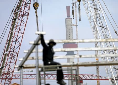 A worker looks on as the Lotus Tower construction site, backed by Chinese investment, is seen behind him (C) in Colombo February 8, 2016. REUTERS/Dinuka Liyanawatte