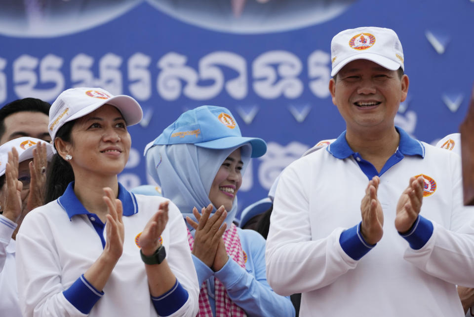 Hun Manet, right, a son of Cambodia Prime Minister Hun Sen, leads a procession together with his wife, Pich Chanmony, left, to mark the end of an election campaign of Cambodian People's Party, in Phnom Penh, Cambodia, Friday, July 21, 2023. Hun Sen says he is ready to hand the premiership to his oldest son, Hun Manet, who heads the country’s army. (AP Photo/Heng Sinith)