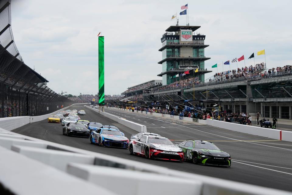 Los pilotos de la NASCAR Cup Series, Tyler Reddick (45) y Denny Hamlin (11), lideran el pelotón en la primera curva después de tomar la bandera verde el domingo 21 de julio de 2024, durante la Brickyard 400 en el Indianapolis Motor Speedway.