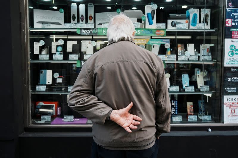 A man looks into the shop window of an electronics store, as Argentina is due to release consumer inflation data for April, in Buenos Aires