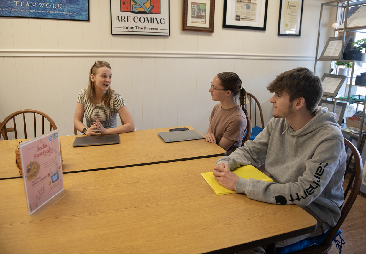 Arasin Hughes, Main Street Ravenna executive director, teams with Ravenna High School seniors Addison Ribelin, 17, and Michael Myers, 18, on the upcoming Jojo Festival in Ravenna.