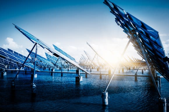 Solar power panels with the sun shining in the background.