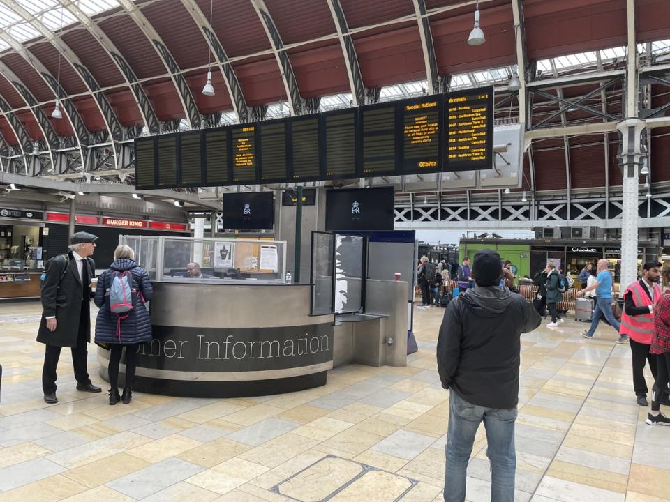 Members of the public look at the travel boards in Paddington Station (PA) (PA Wire)