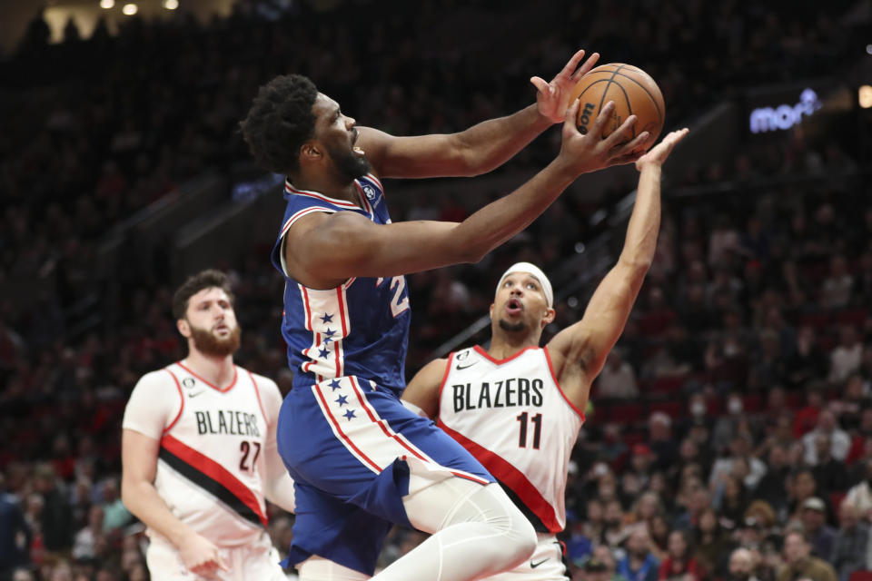 Philadelphia 76ers center Joel Embiid (21) drives past Portland Trail Blazers center Jusuf Nurkic (27) and guard Josh Hart (11) during the first half of an NBA basketball game in Portland, Ore., Thursday, Jan. 19, 2023. (AP Photo/Amanda Loman)