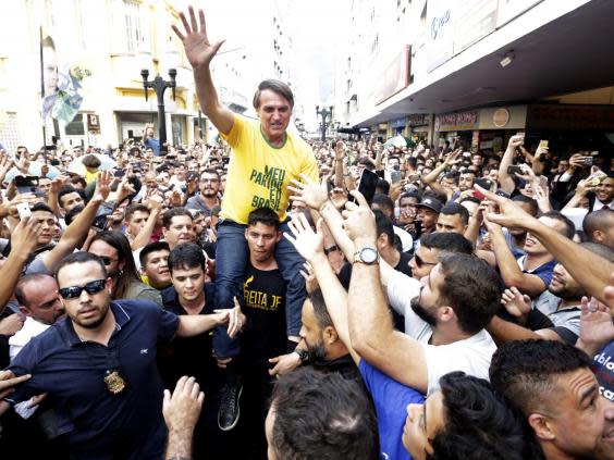 Presidential candidate Jair Bolsonaro is taken on the shoulders of a supporter moments before being stabbed during a campaign rally (AP)