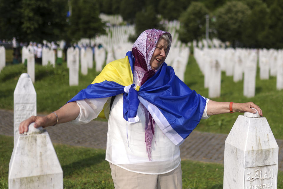 A Bosnian muslim woman mourns next to the graves of her children and husband, victims of the Srebrenica genocide, at the Memorial Centre in Potocari, Bosnia, Tuesday, July 11, 2023. Thousands converge on the eastern Bosnian town of Srebrenica to commemorate the 28th anniversary on Monday of Europe's only acknowledged genocide since World War II. (AP Photo/Armin Durgut)