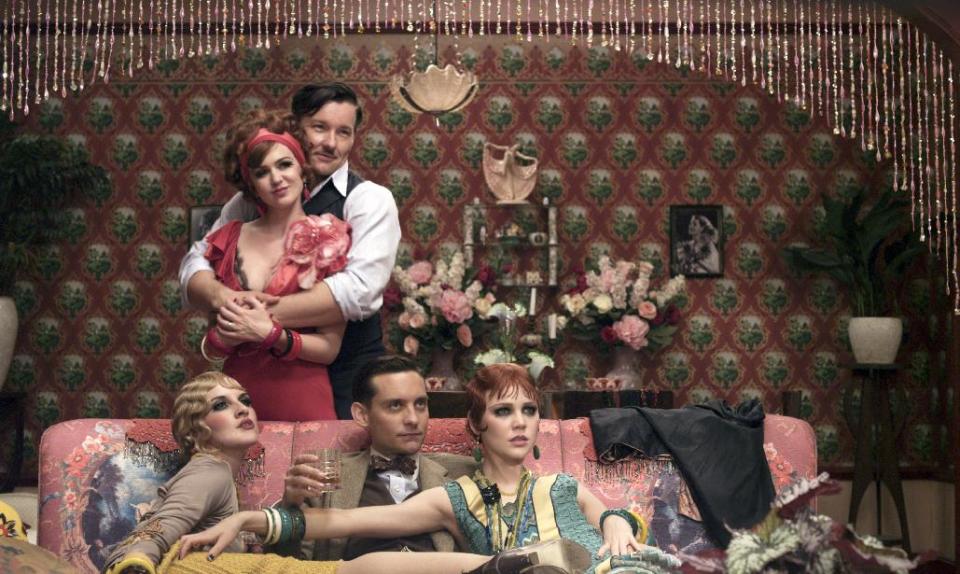 This film publicity image released by Warner Bros. Pictures shows Isla Fisher as Myrtle Wilson, standing left, Joel Edgerton as Tom Buchanan, standing right, Adelaide Clemens as Catherine, seated from left, Tobey Maguire as Nick Carraway and Kate Mulvany as Mrs. McKee in a scene from "The Great Gatsby." (AP Photo/Warner Bros. Pictures)