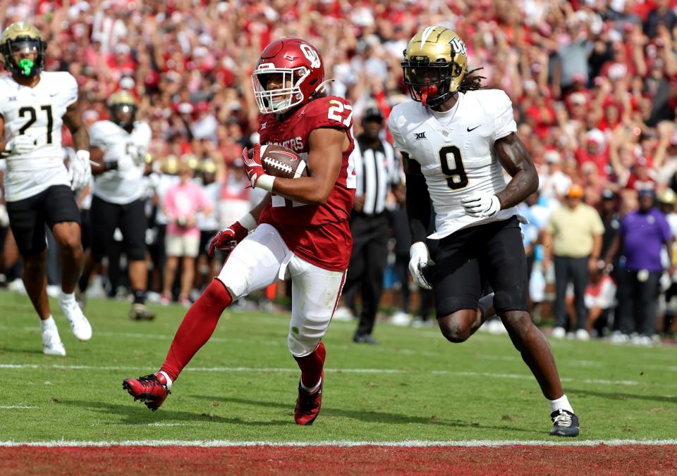 Oklahoma's Gavin Sawchuk (27) scores a touchdown as UCF's Jireh Wilson (9) defends in the second half of the college football game between the University of Oklahoma Sooners and the University of Central Florida Knights at Gaylord Family Oklahoma-Memorial Stadium in Norman, Okla., Saturday, Oct., 21, 2023.