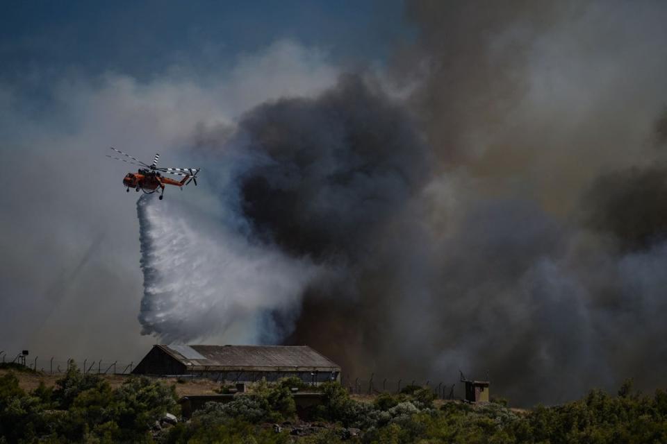 A helicopter sprays water above a military camp during a wildfire in Keratea, near Athens, on June 30, 2024 (AFP via Getty Images)