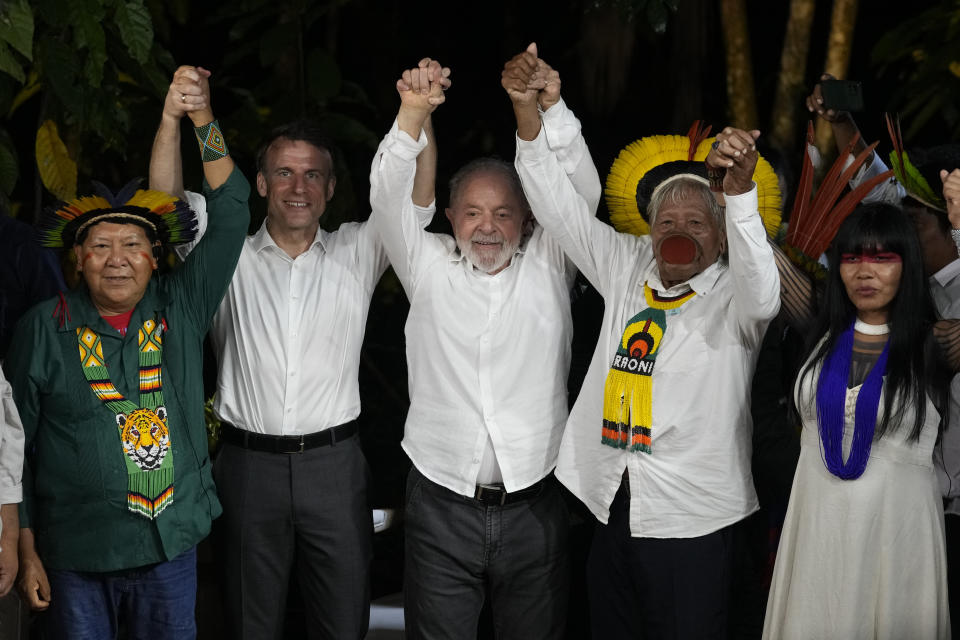 Davi Kopenawa, Yanomami leader, from left to right, French President Emmanuel Macron, Brazil's President Luiz Inacio Lula da Silva, Chief Raoni Metuktire and Chief Watatakalu Yawalapiti, leader of the Xingu women's movement, raise their arms in unison as they pose for a photo on Combu Island, near Belem, Para state, Brazil, Tuesday, March 26, 2024. (AP Photo/Eraldo Peres)