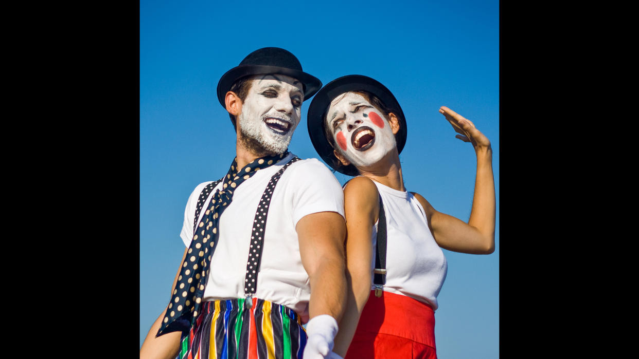 Two mimes standing against blue sky.