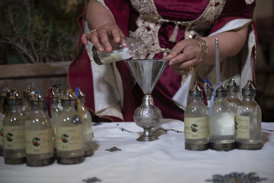 A woman packages orange blossom water in a cultural center in Marrakech, Morocco, Saturday, March 23, 2024. Moroccan cities are heralding in this year's spring with orange blossoms by distilling them using traditional methods. Orange blossom water is mostly used in Moroccan pastries or mint tea and sprinkled over heads and hands in religious ceremonies. (AP Photo/Mosa'ab Elshamy)
