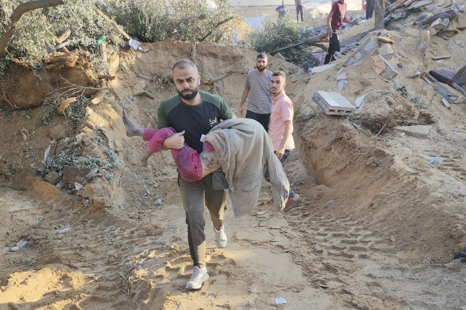 Un palestino lleva a una niña asesinada en ataques aéreos israelíes en Deir el-Balah, en la Franja de Gaza, el domingo 15 de octubre de 2023. (AP Foto/Hasan Islayeh)